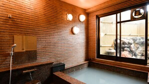 A modern bathroom with a wooden ceiling, a large window, and a stone floor. - Ryokan Tamura (Kusatsu)