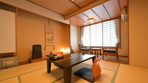 A traditional Japanese room with tatami flooring, a low table, and sliding doors. - Ryokan Tamura (Kusatsu)