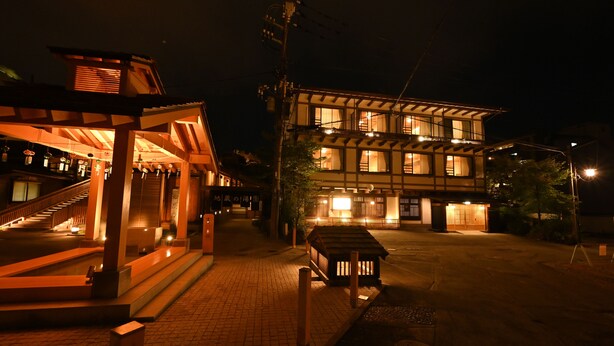 A traditional Japanese building with a wooden structure and a tiled roof, featuring a staircase and a small wooden bench in front. - Ryokan Tamura (Kusatsu)