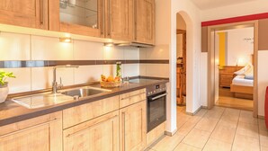 Uma cozinha moderna com armários de madeira, uma pia de aço inoxidável e um forno embutido.