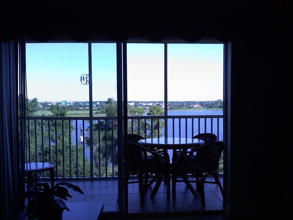 A balcony with a view of a lake and surrounding greenery.