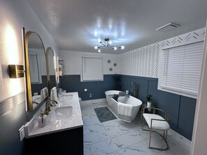 A modern bathroom with a freestanding bathtub, a large mirror, and a vanity with a sink.