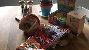 Ett träbord med olika sorters mat, en krukväxt och en teask.