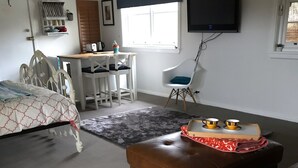 Ett sovrum med en säng, ett skrivbord, en stol, en tv och ett fönster.