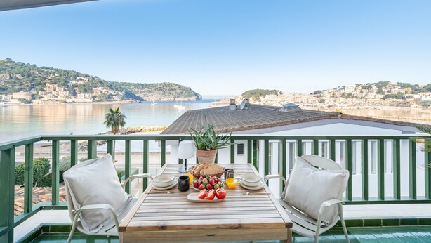 Una terraza con una mesa para dos, con vistas a un pueblo costero y al mar.