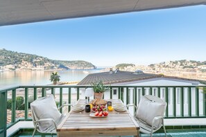 Eine Terrasse mit Tisch für zwei Personen mit Blick auf eine Küstenstadt und das Meer.