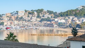Un pueblo costero con edificios a lo largo del paseo marítimo, un puerto deportivo y una playa de arena.