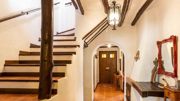 Una escala de fusta amb barana, que condueix a una porta amb un petit finestral.