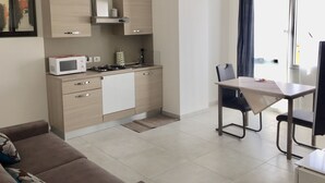 Una cocina moderna con microondas, estufa y armarios. Hay una mesa de comedor con sillas y un sofá en la zona de estar.