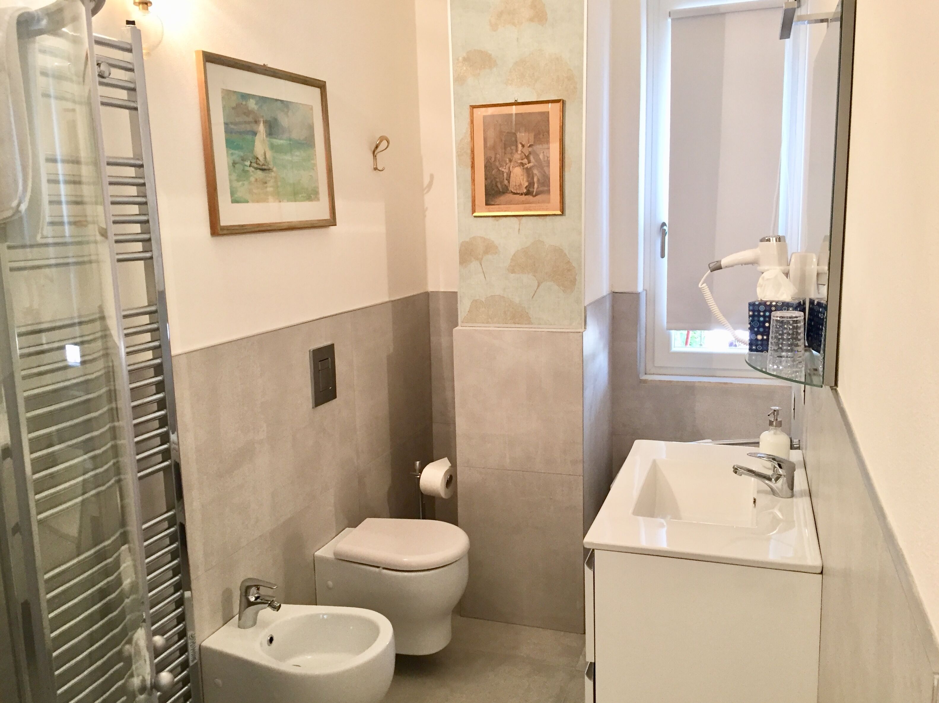 Une salle de bain comprenant des toilettes, un bidet, un lavabo et un porte-serviettes.