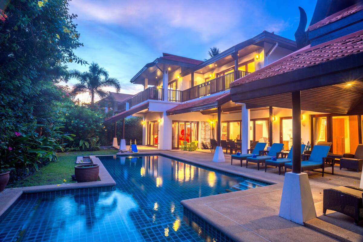 A hotel with a swimming pool, outdoor seating, and a well-lit facade.