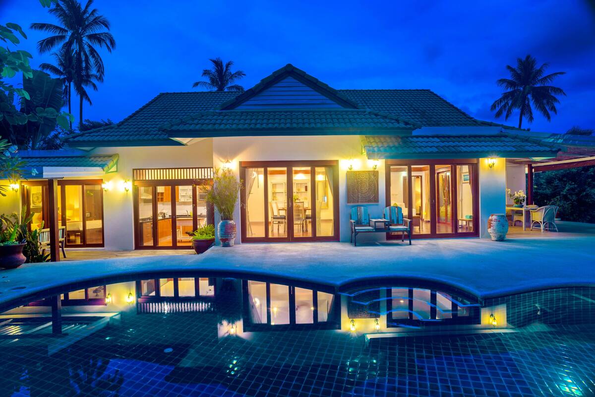 A resort with a swimming pool, a covered patio, and a well-lit entrance.