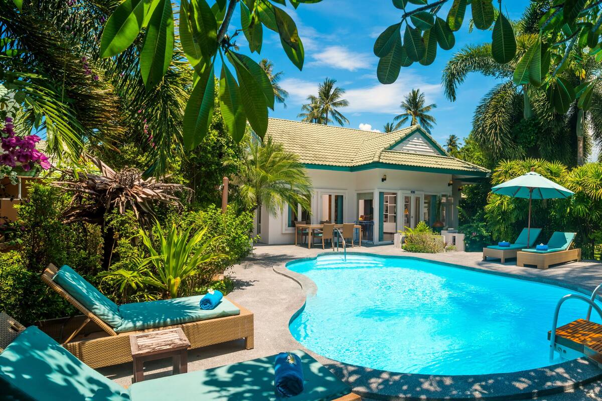 A swimming pool surrounded by lounge chairs and a building with a tiled roof.