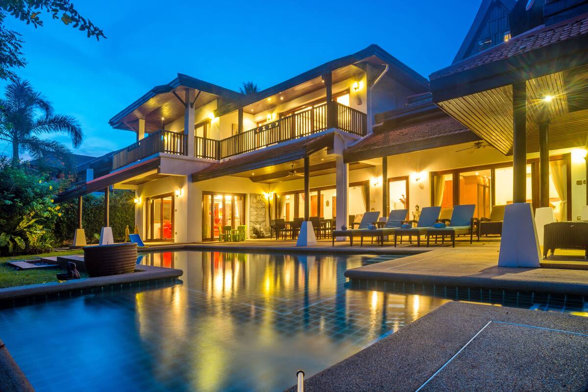 A two-story resort with a swimming pool, outdoor seating, and a well-lit entrance.