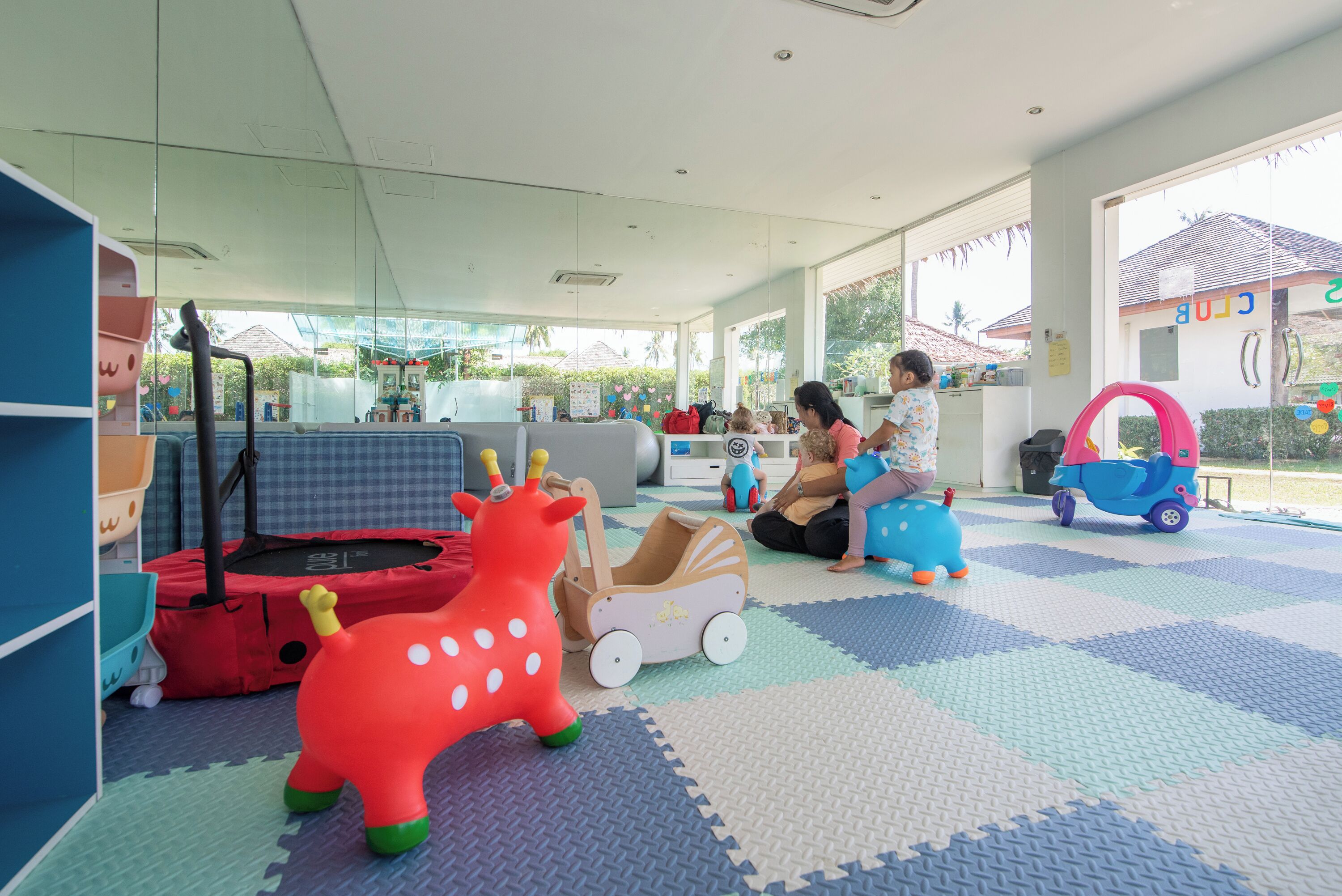 A children's play area with colorful toys, a trampoline, and a checkered floor.