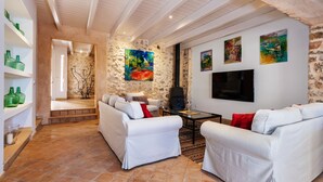 Ein Wohnzimmer mit weißen Sofas, einem Fernseher und Kunstwerken an den Wänden.