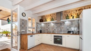 Eine Küche mit weißen Schränken, einer gefliesten Spritzschutzwand und einer Holz Arbeitsplatte.