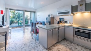 Eine moderne Küche mit Marmorboden, integrierten Geräten und einem Essbereich mit Ausblick.