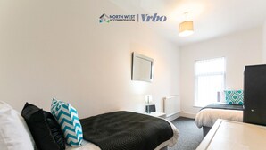 Une chambre d’hôtel avec un lit, une table de chevet, une lampe et une fenêtre.