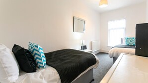 Une chambre d’hôtel avec un lit, une table de chevet, une lampe et une fenêtre.