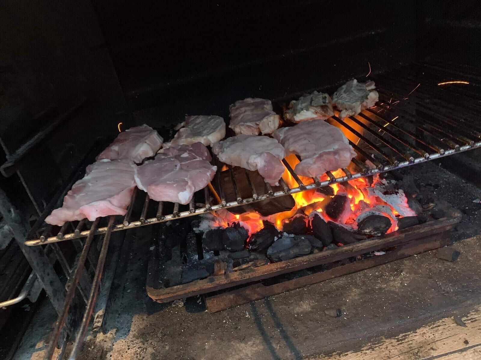 Raw meat being grilled over an open flame.