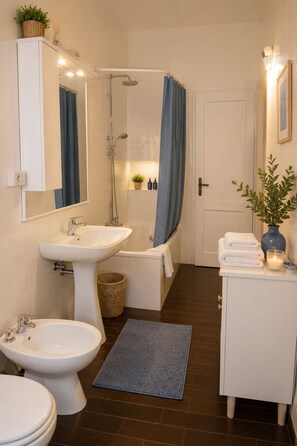 A bathroom with a sink, bidet, toilet, shower, and bathtub.