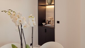 Et moderne spiseområde med et rundt bord, hvide stole og en potteplante med hvide orkidéer.