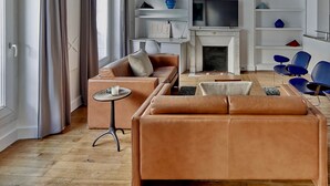 En moderne stue med lædersofaer, pejs, et fladskærms-tv og et minimalistisk reolsystem.