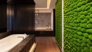 A modern bathroom with a large bathtub, wooden paneling, and a green textured wall. - Kantharyar Serviced Apartment (Yangon)