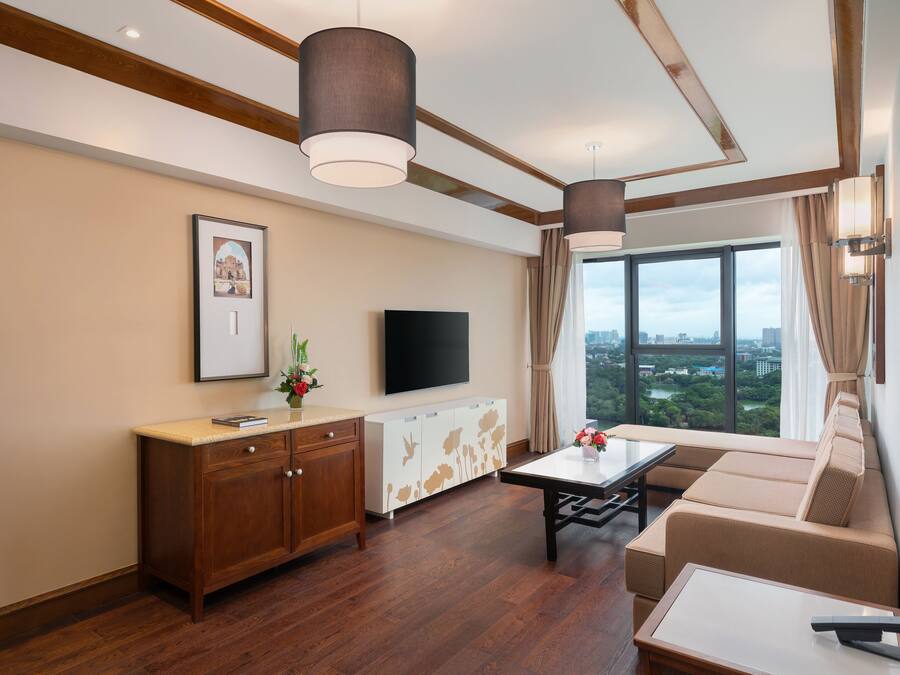 Una sala de estar moderna con un sofá, una mesa de centro, un televisor y un ventanal con vistas a la ciudad.