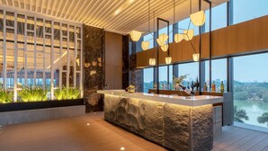 A modern bar area with a stone counter, large windows, and a view of the cityscape. - Kantharyar Serviced Apartment (Yangon)
