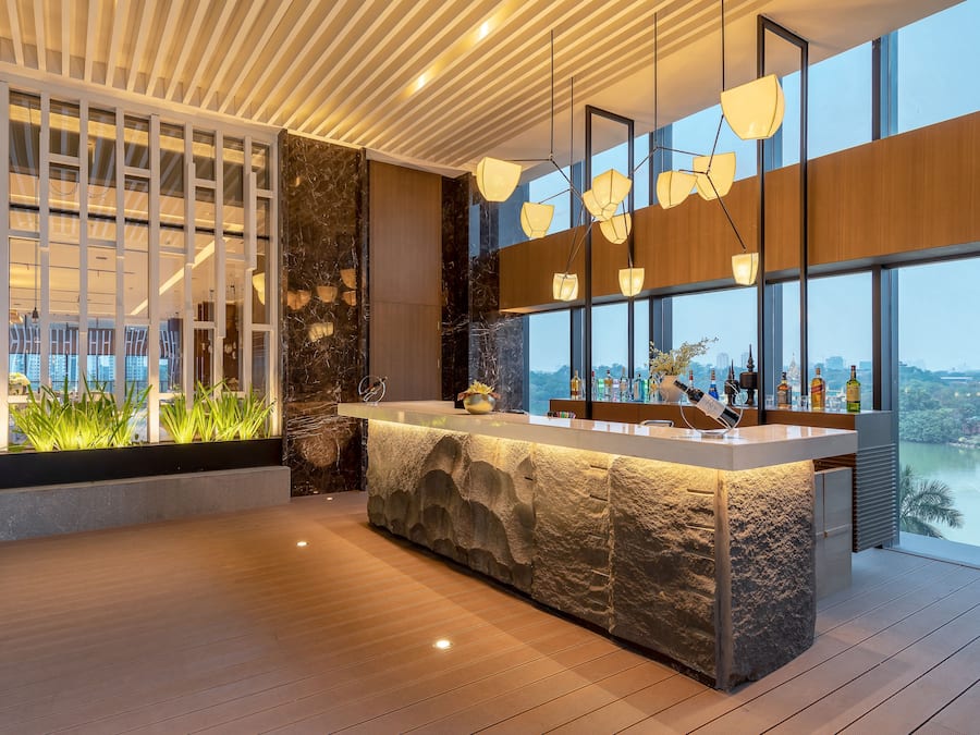 A modern bar area with a stone counter, large windows, and a view of the cityscape.