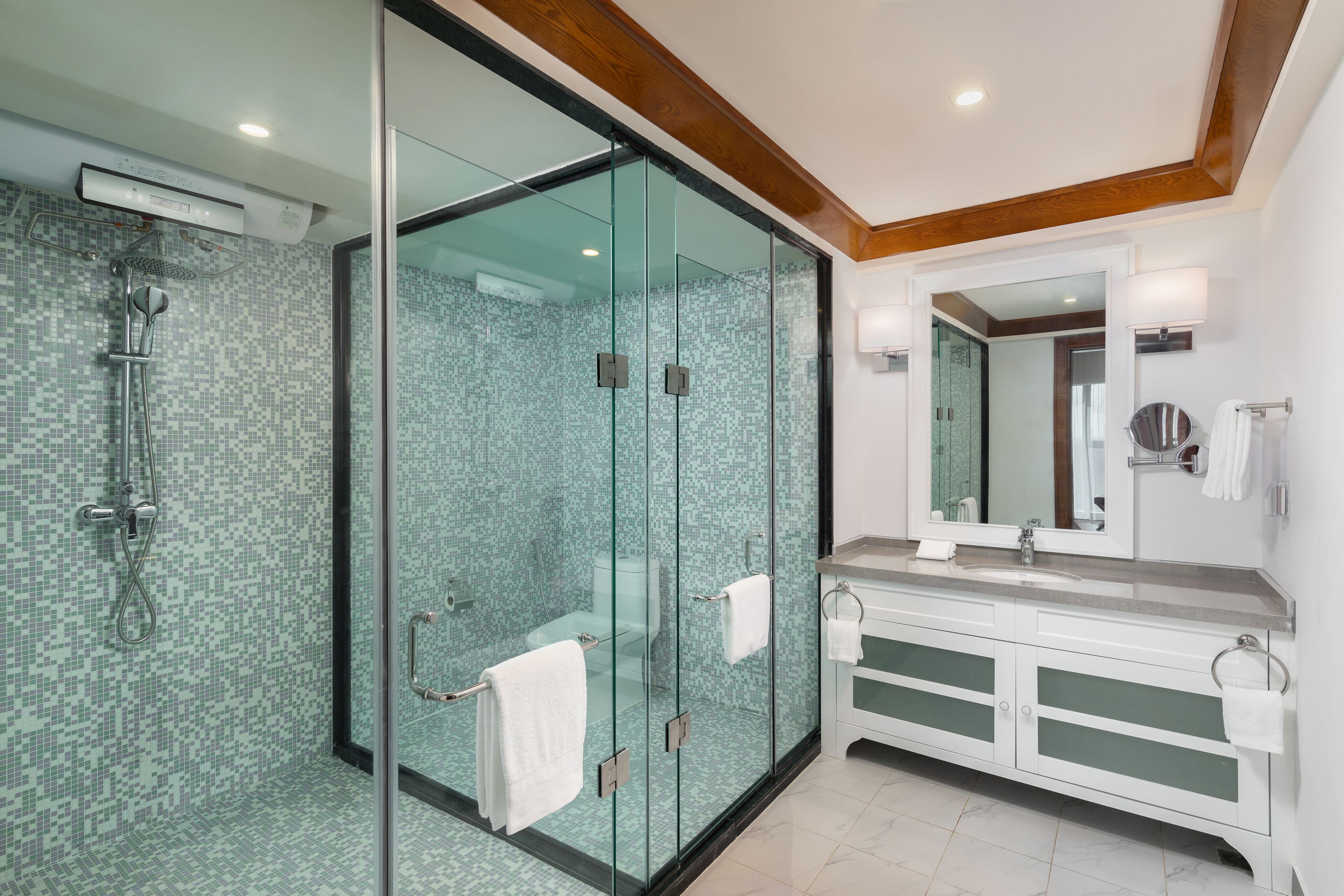 A modern bathroom with a glass-enclosed shower, a large mirror, and a white vanity with a sink.
