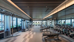 A modern gym with various exercise equipment, large windows, and a checkered floor. - Kantharyar Serviced Apartment (Yangon)