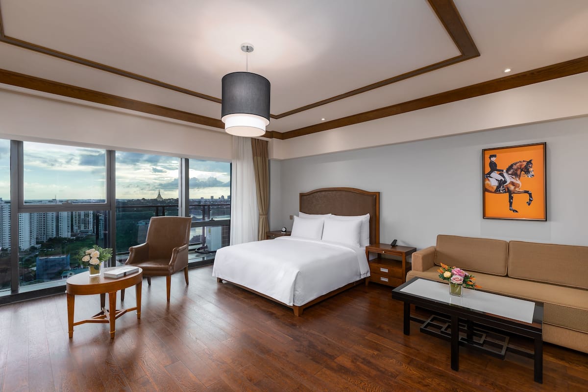 Une chambre d’hôtel moderne avec un grand lit, un canapé, une petite table et une vue sur la ville.