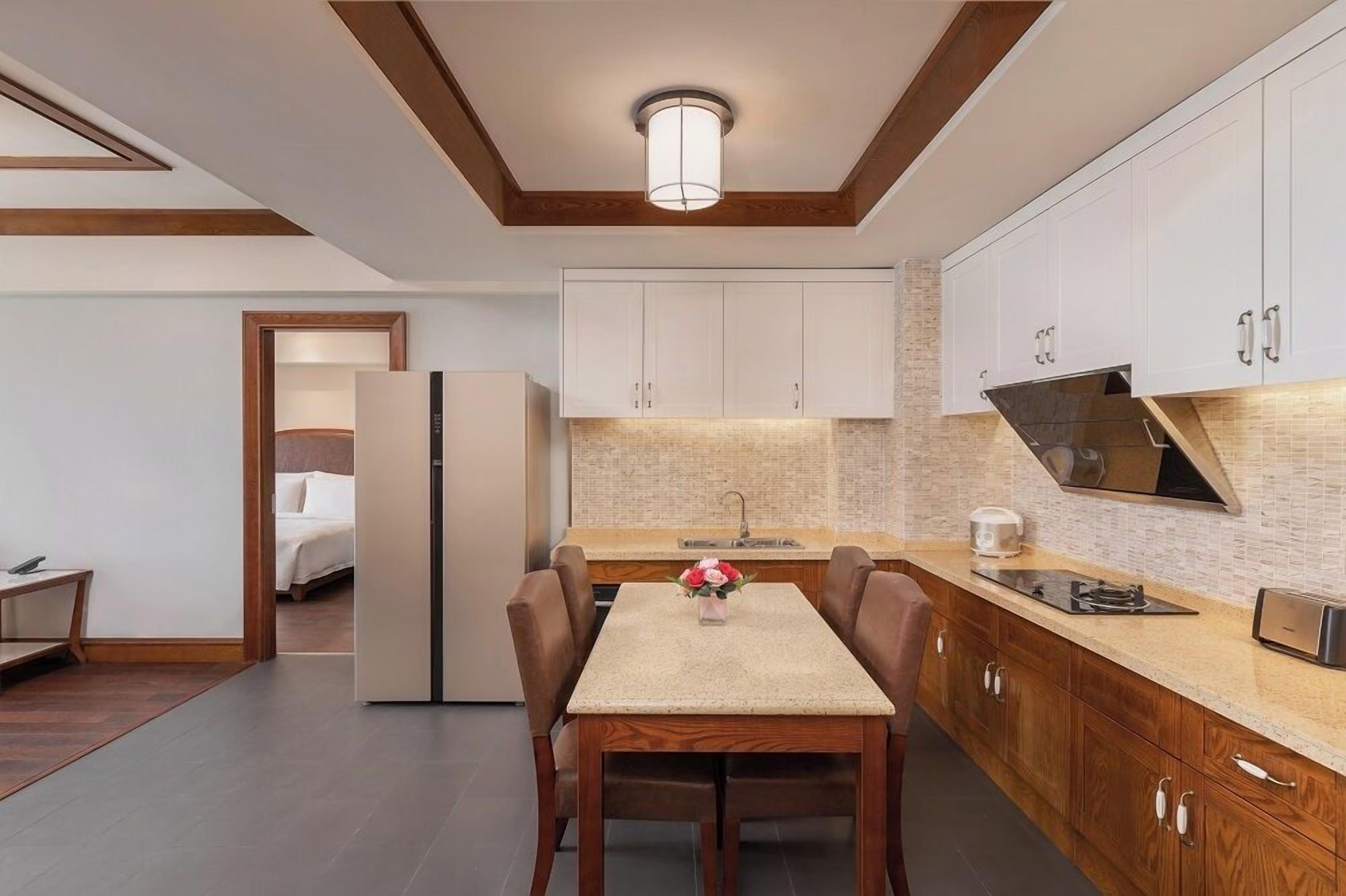 A modern kitchen with white cabinets, a central island, and a dining area with a table and chairs.