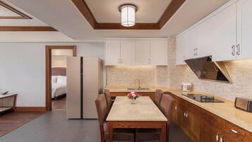 A modern kitchen with white cabinets, a central island, and a dining area with a table and chairs.