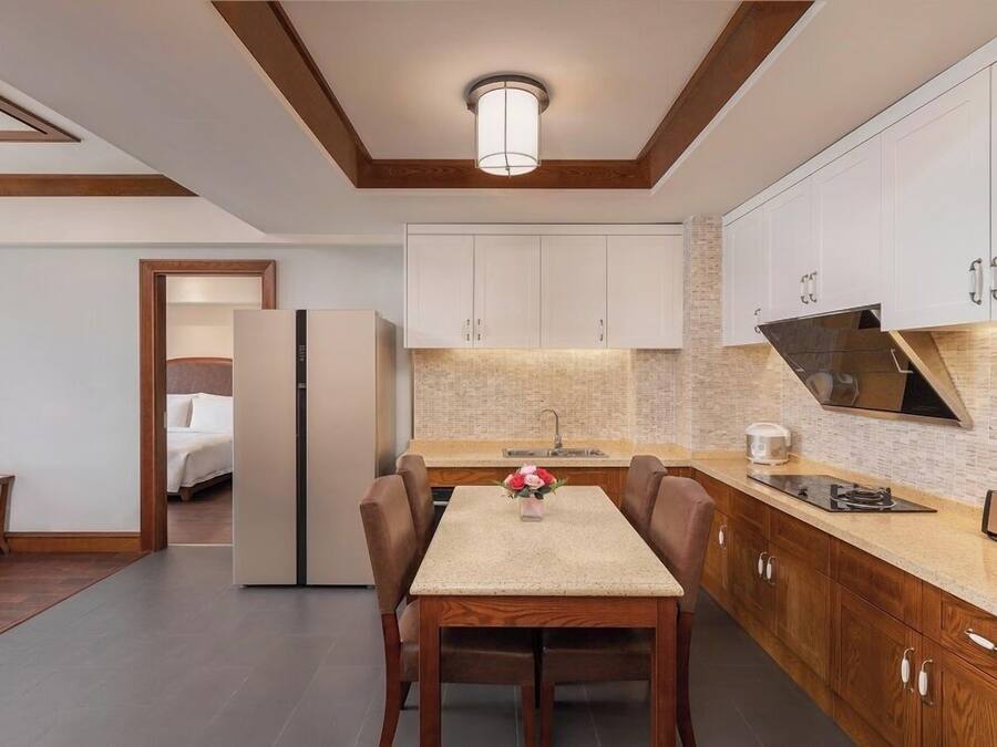 A modern kitchen with white cabinets, a central island, and a dining area with a table and chairs.