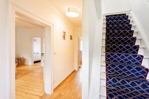 Stunning staircase with a geometric-patterned carpet, framed artwork, and a door leading to another room.