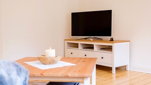 Ein modernes Wohnzimmer mit einem Holztisch, einem weißen Schrank und einem Flachbildfernseher.
