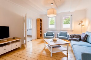 Relax in a stylish living room with a flat-screen TV, comfortable seating, and a large window.