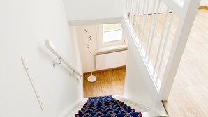 Eine Treppe mit gemustertem Teppich, weißen Wänden und Holzdielen.