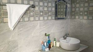 Un baño con un lavabo blanco, un espejo y una toalla colgada en un perchero.