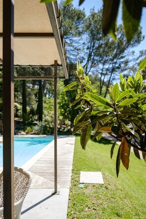 Relax by the serene pool surrounded by lush greenery and a well-maintained lawn.