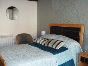 Cozy retreat with a neatly made bed, wooden headboard, and comfortable chair.