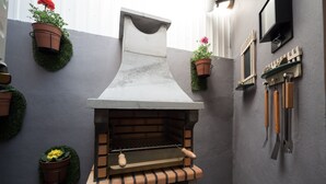 Un horno de piedra al aire libre con base de ladrillo, rodeado de macetas y herramientas de jardinería.