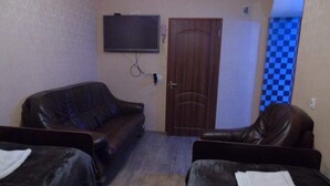 Ein Zimmer mit zwei Ledersofas, einer Holztür und einem an der Wand befestigten Fernseher.