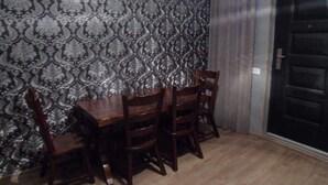 Ein Essbereich mit gemustertem Wandpapier, einem Holztisch und vier Stühlen.