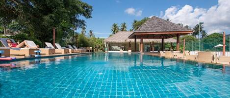 A clear blue pool with lounge chairs and a gazebo.