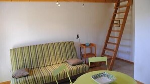 A room with a striped sofa, a small table with a bowl, and a wooden ladder against the wall.